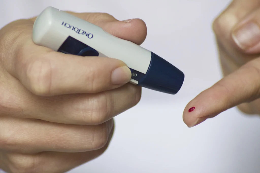 Person checking blood sugar level using a glucometer with a finger prick blood sample