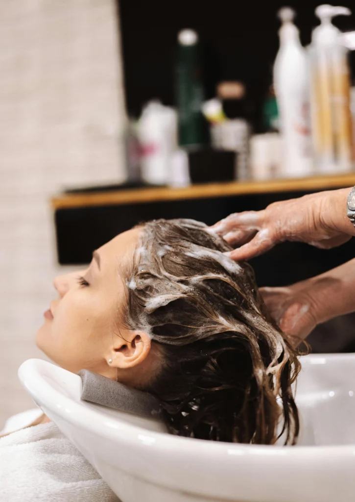 Can dandruff cause hair loss? Woman washing hair with anti-dandruff shampoo for scalp treatment