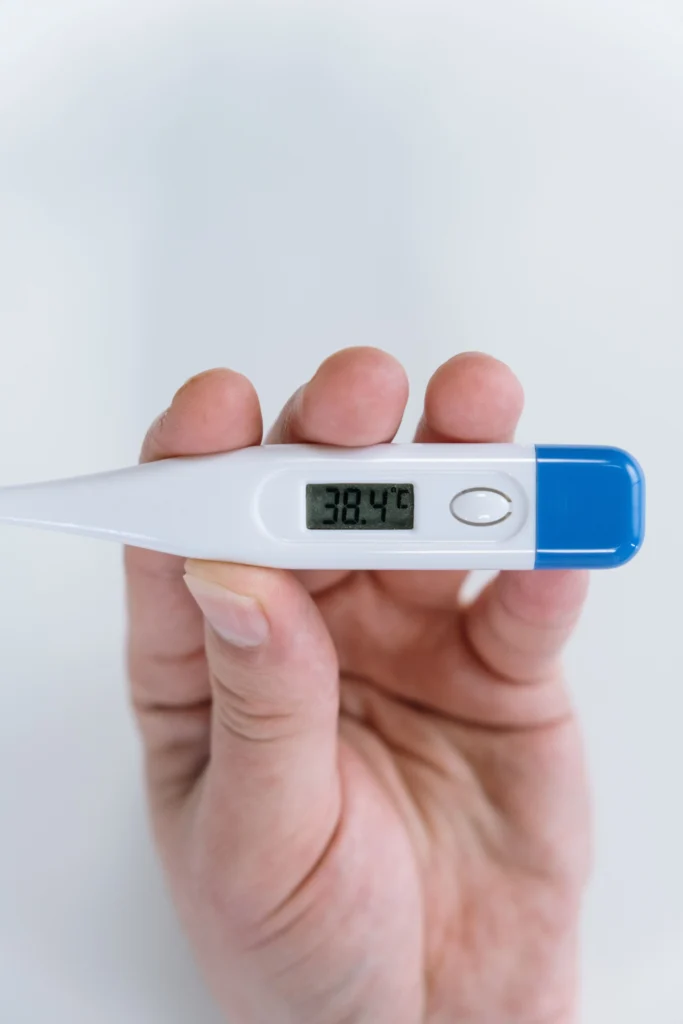 Digital thermometer showing 38.4°C fever temperature reading in an adult patient