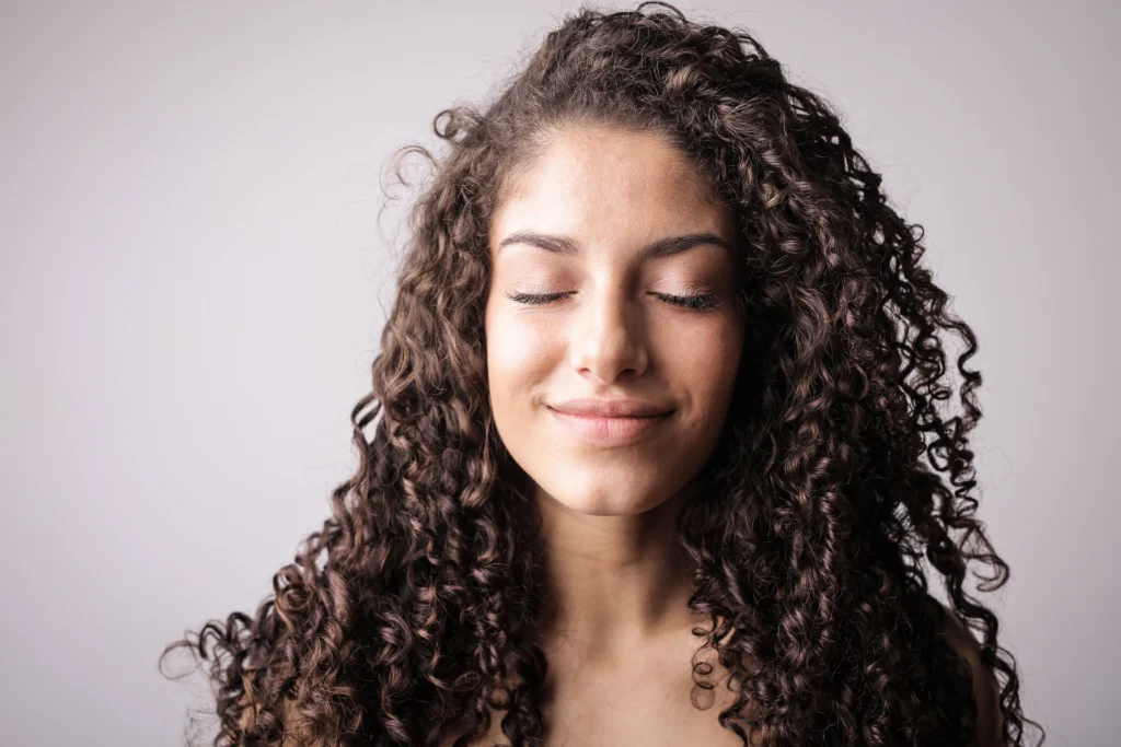 Woman with healthy curly hair demonstrating a hair care routine for strong, shiny, and well-maintained hair