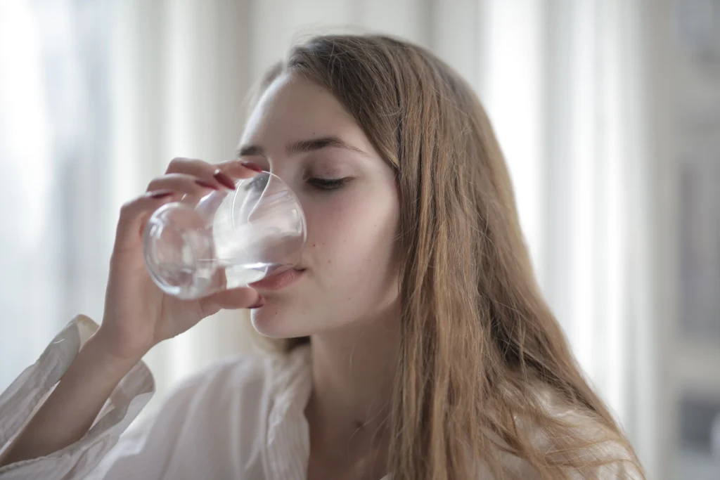 Person drinking water to support healthy hydration as part of a dry skin (xerosis) skincare routine.