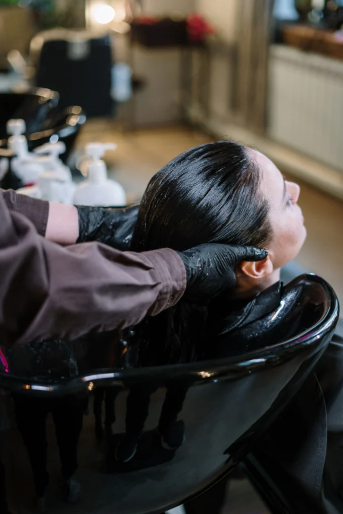 Woman getting a hair wash before a keratin treatment for hair care at a professional salon